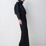 Person wearing a black outfit standing against a white background