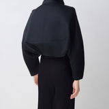 Person wearing a black outfit with a plain background