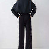 Person wearing a black outfit with wide-leg pants on a white background