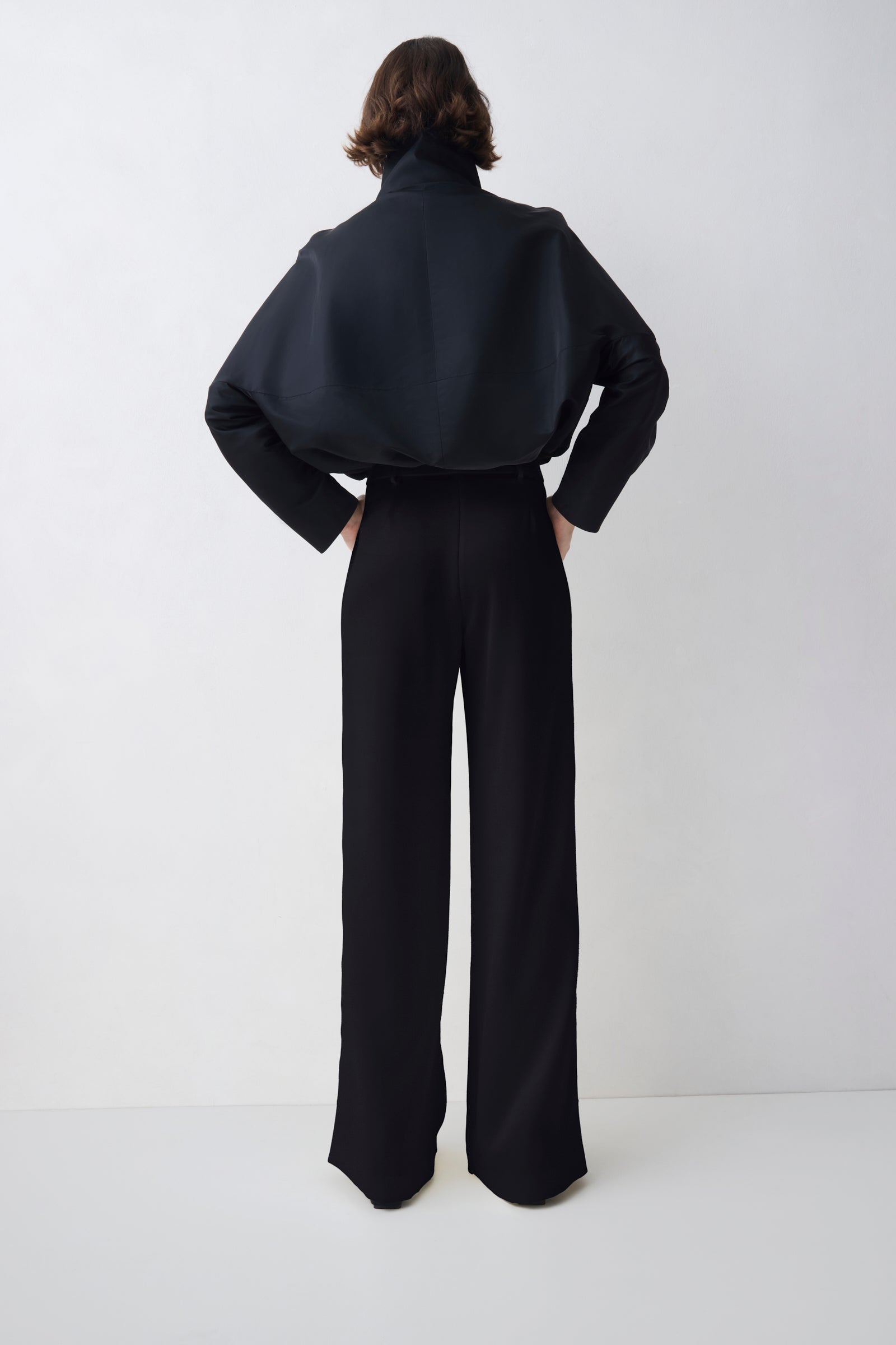 Person wearing a black outfit with wide-leg pants on a white background