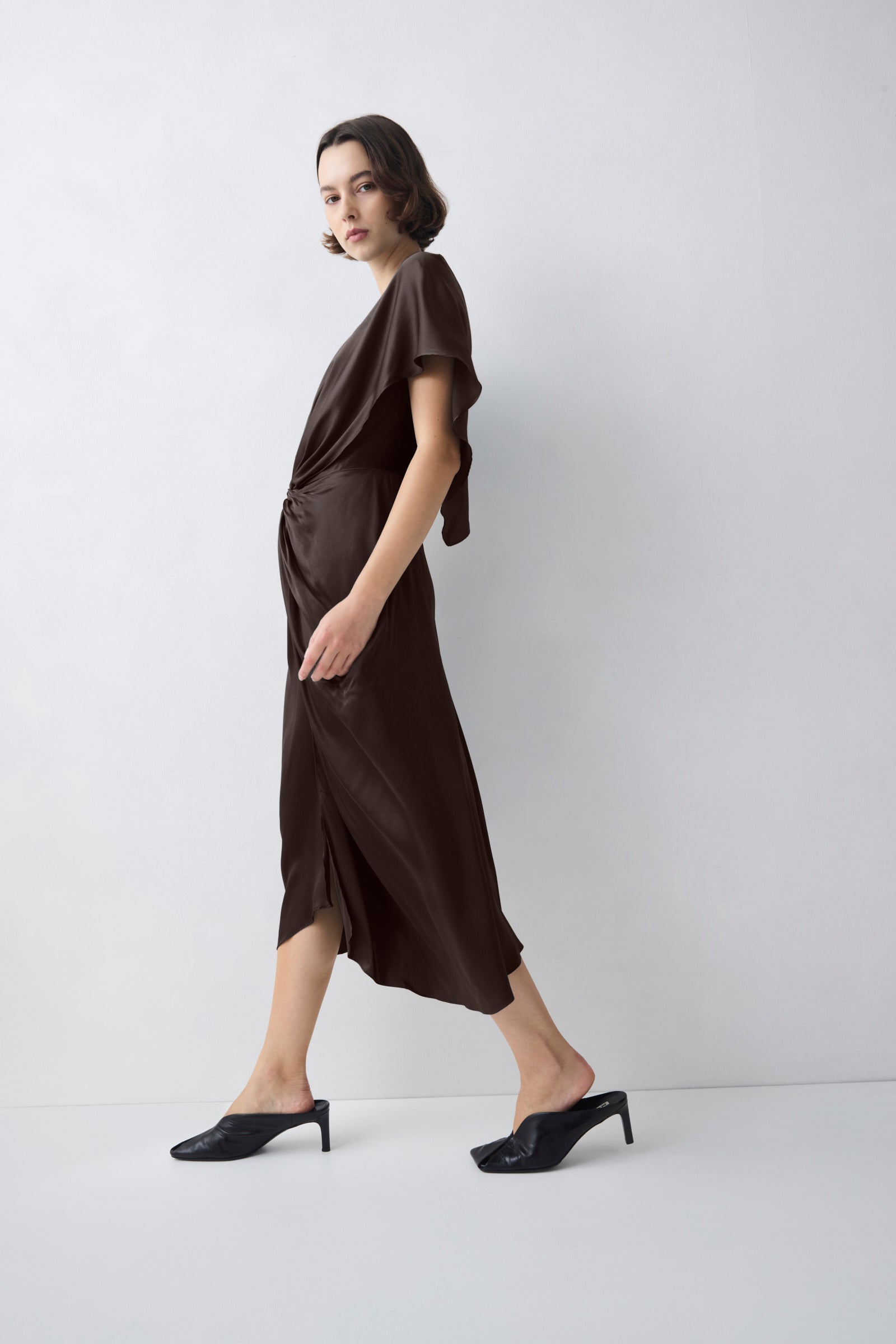 Woman wearing a brown dress standing against a white background