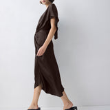 Woman wearing a brown dress standing against a white background