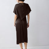 Woman wearing a brown dress with a cape-like feature on a white background