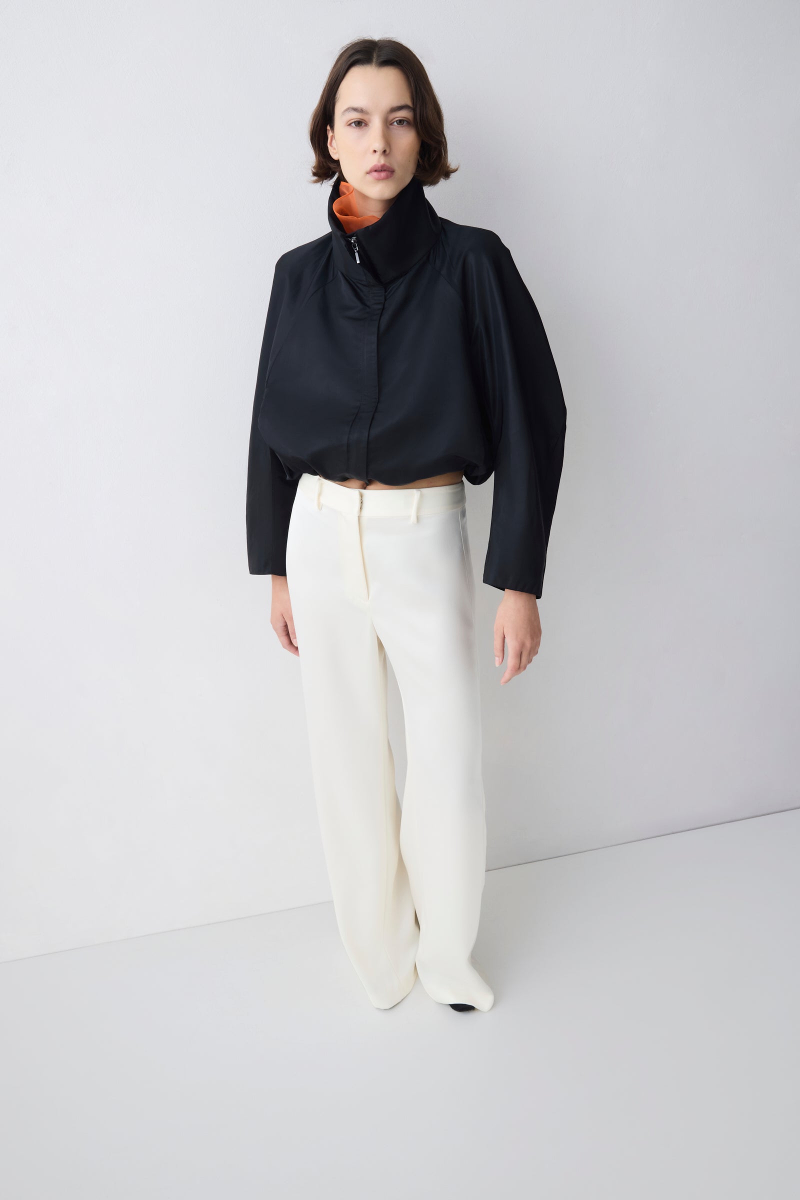 Person wearing a black top and white pants on a plain background