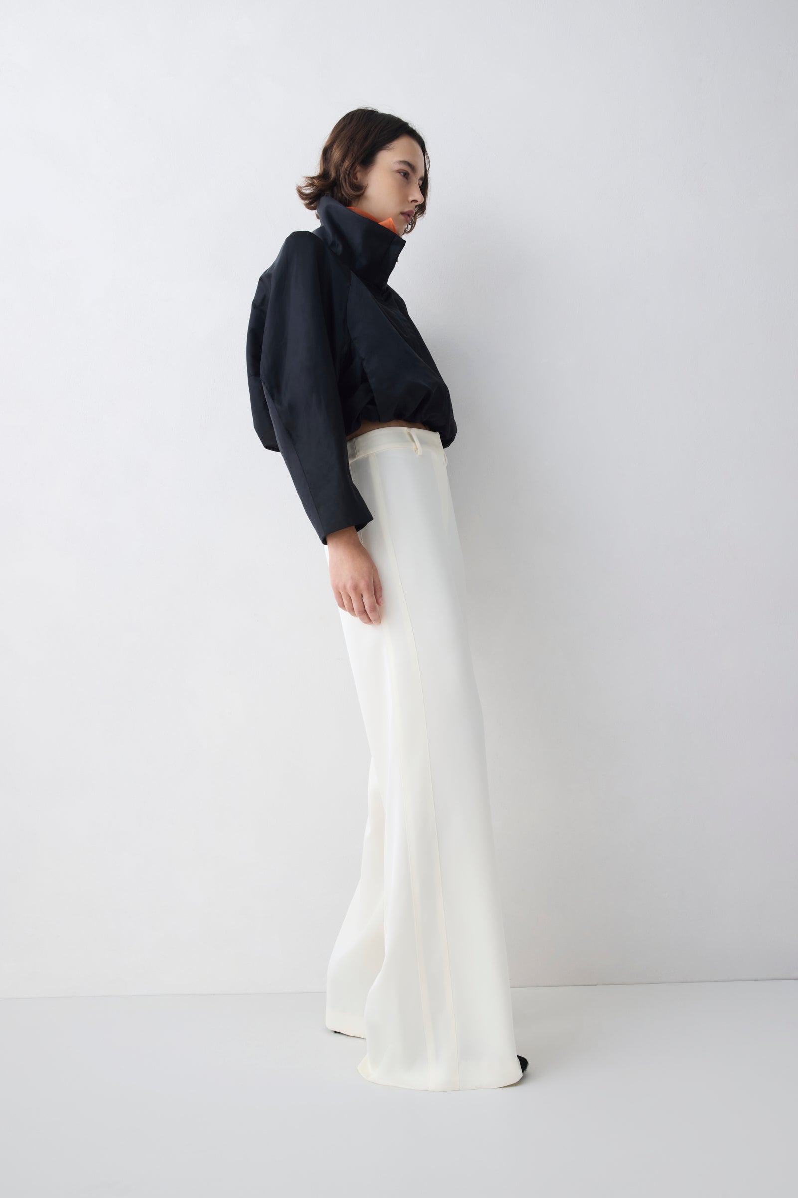Person wearing a black turtleneck and white pants on a white background