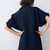 Person wearing a navy blue coat against a white background