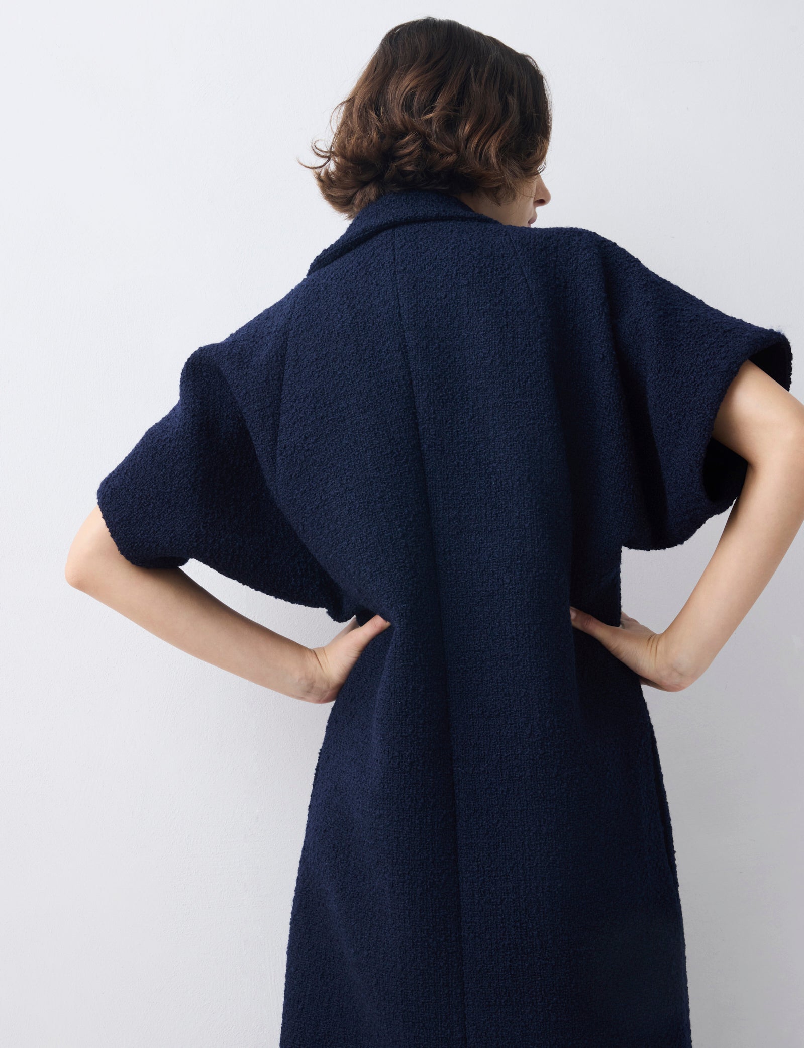 Person wearing a navy blue coat against a white background