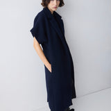 Person wearing a long dark blue coat against a white background