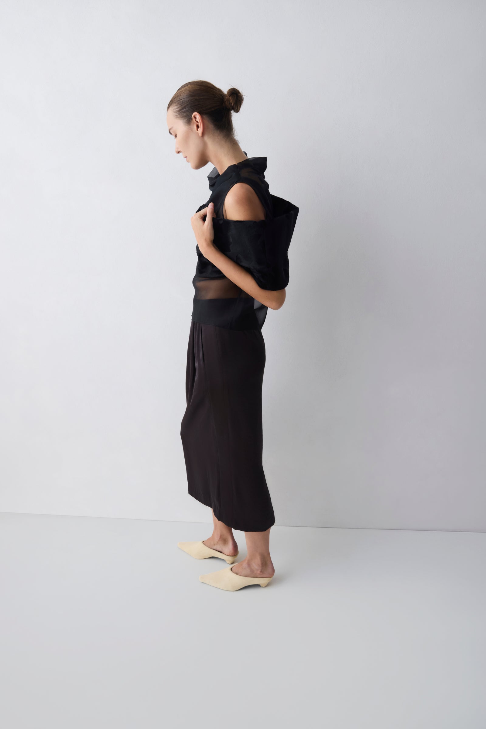 Person wearing a black outfit with sheer details on a white background