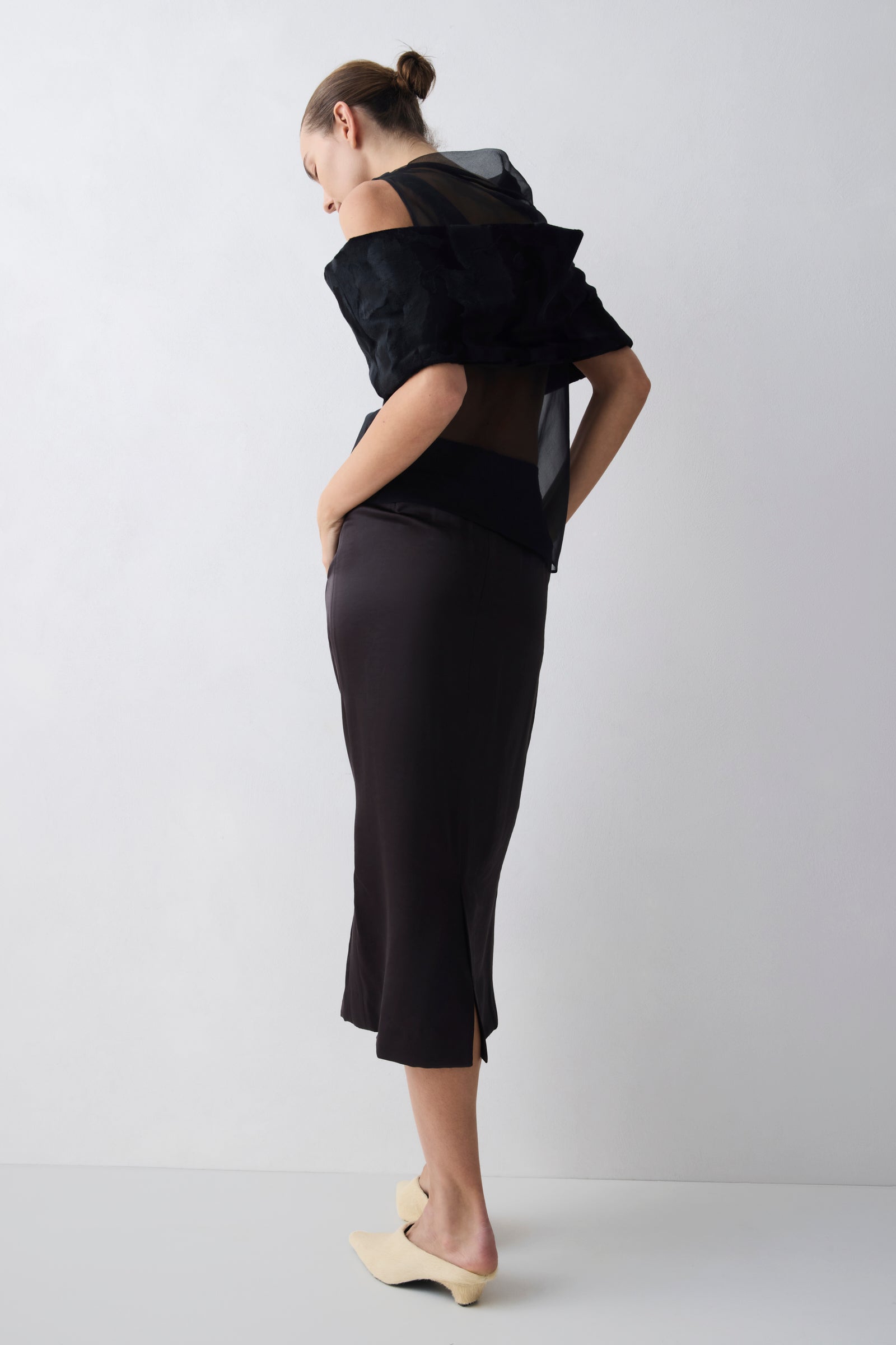 Person wearing a black dress with a unique back design on a white background
