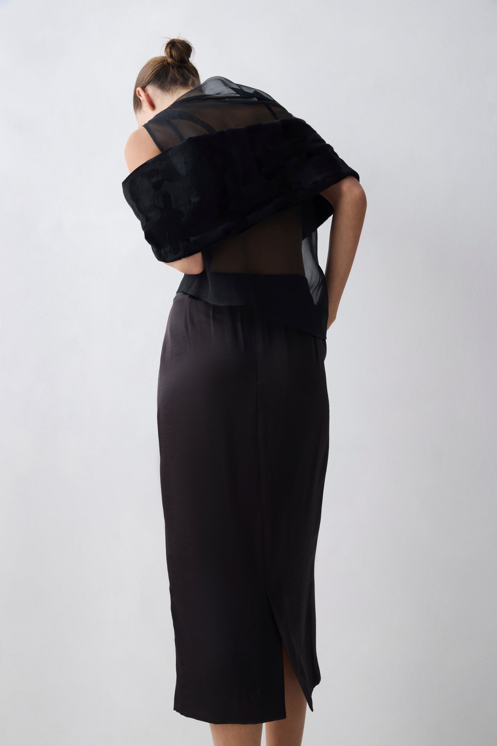 Person wearing a black dress with sheer overlay on a white background