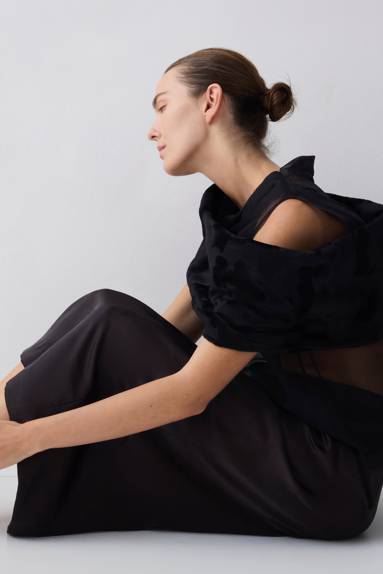 Woman wearing a black outfit sitting on a white background