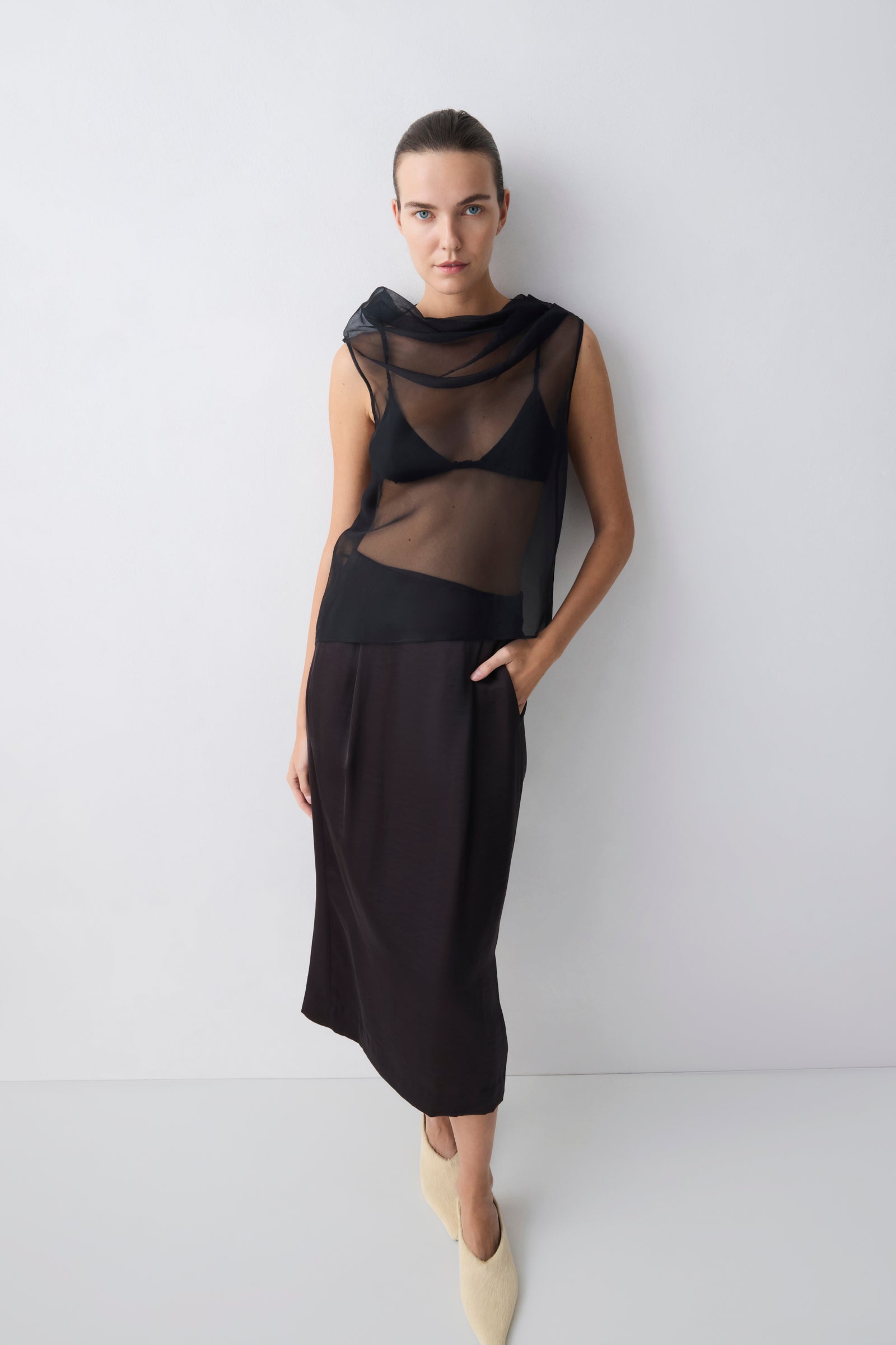 Woman wearing a black dress with sheer panels against a white background