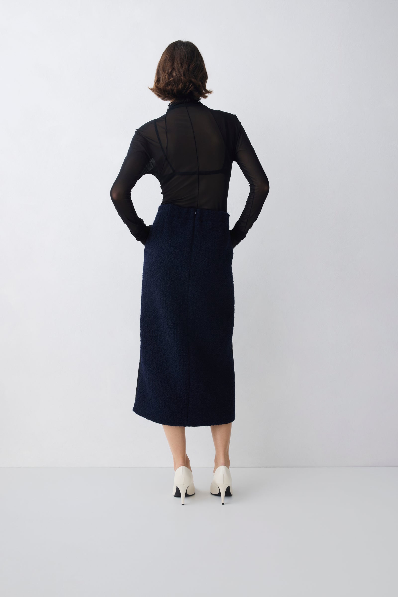 Person wearing a black top and navy skirt against a white background
