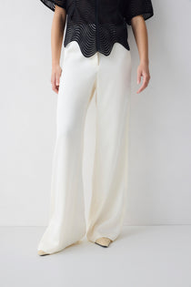 Person wearing a black top and white pants on a plain background