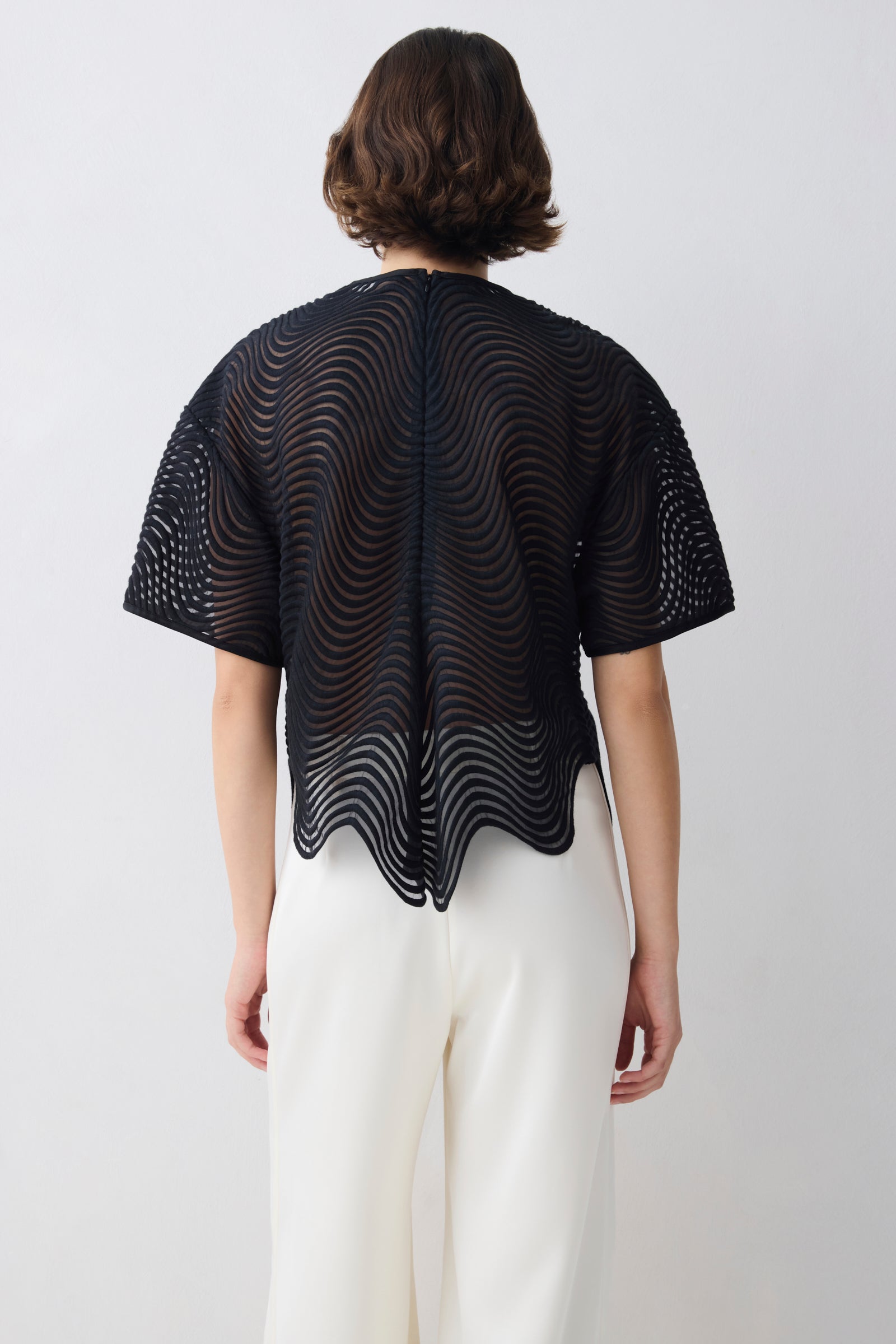 Person wearing a black, wave-patterned top on a white background