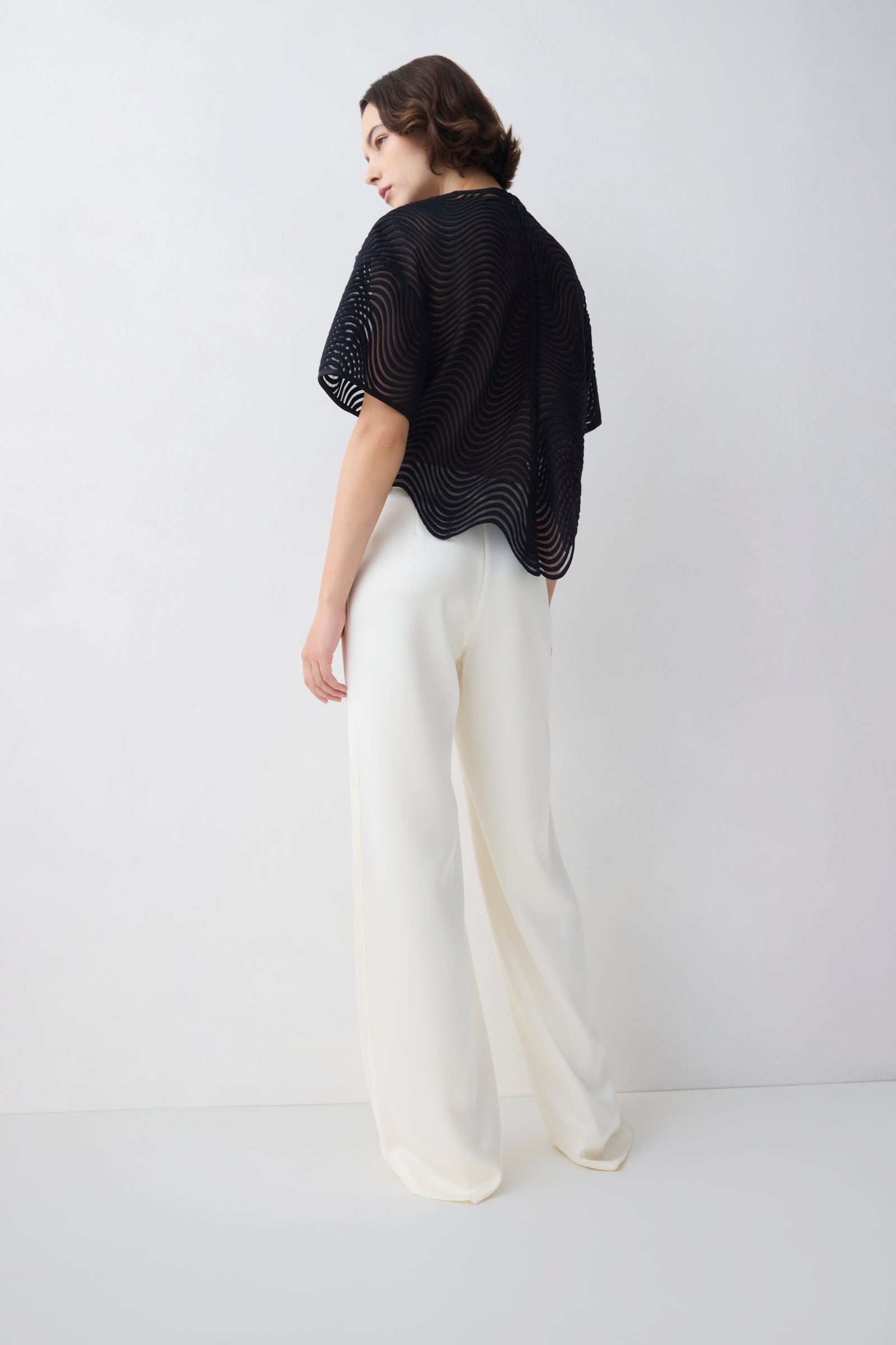 Person wearing a black top and white pants on a white background