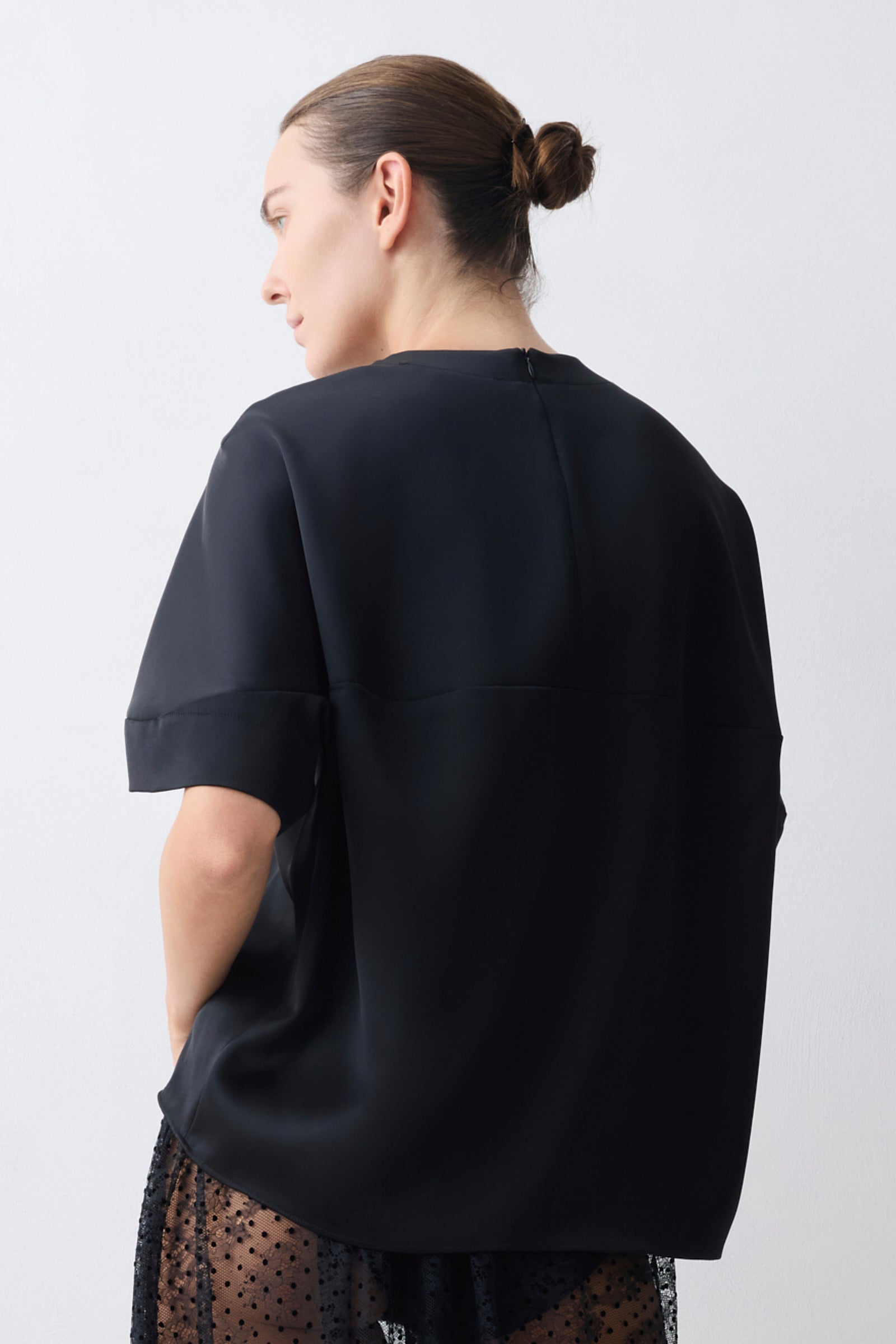 Person wearing a black oversized shirt against a white background