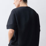 Person wearing a black oversized shirt against a white background