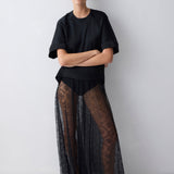 Person wearing a black outfit with sheer black skirt on a white background