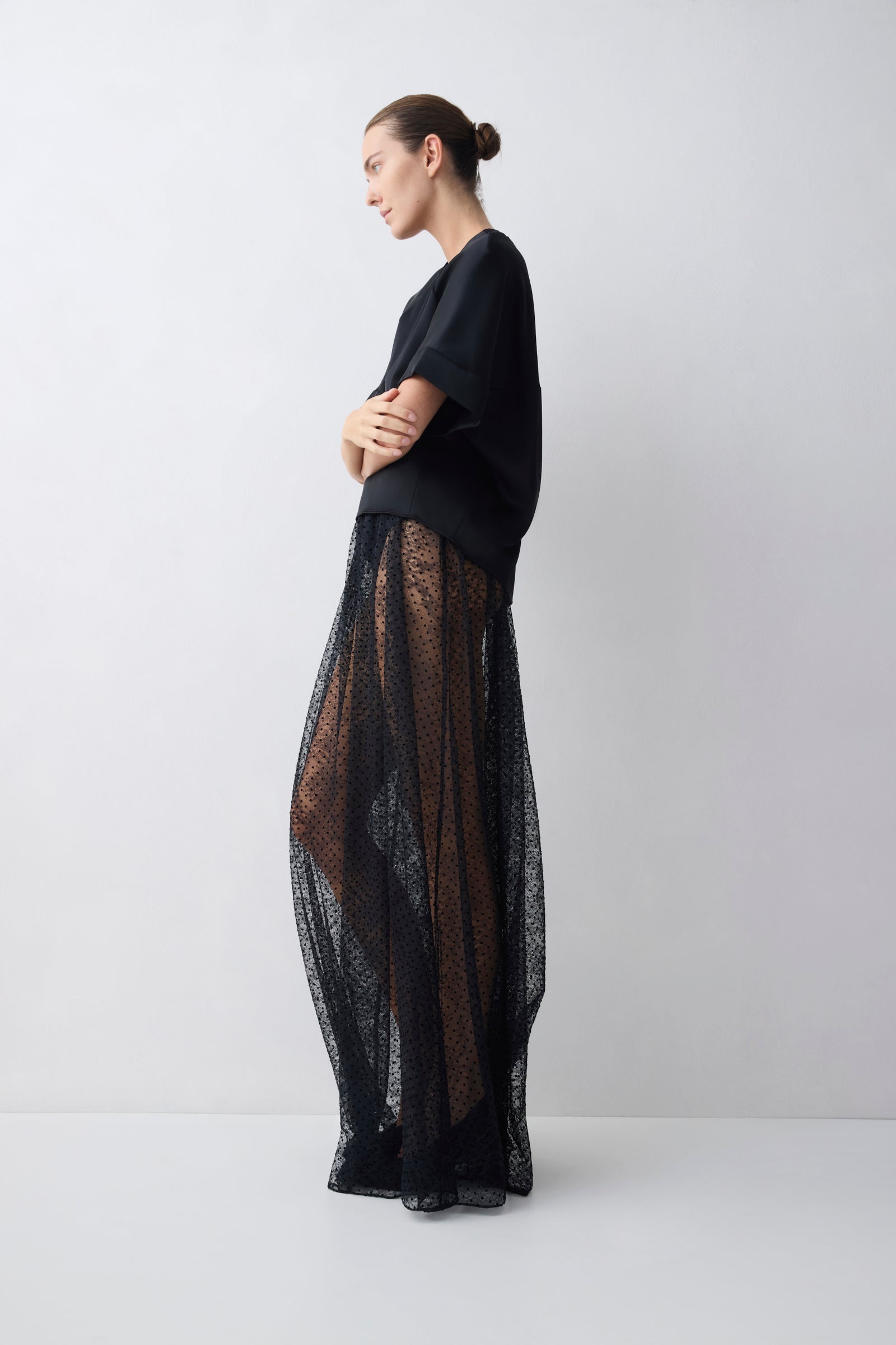 Woman wearing a black outfit with sheer overlay on a white background