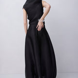 A woman wearing a sleeveless black maxi dress, shown from the back against a light gray studio background.