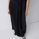 Person wearing black wide-leg pants and a black top on a white background
