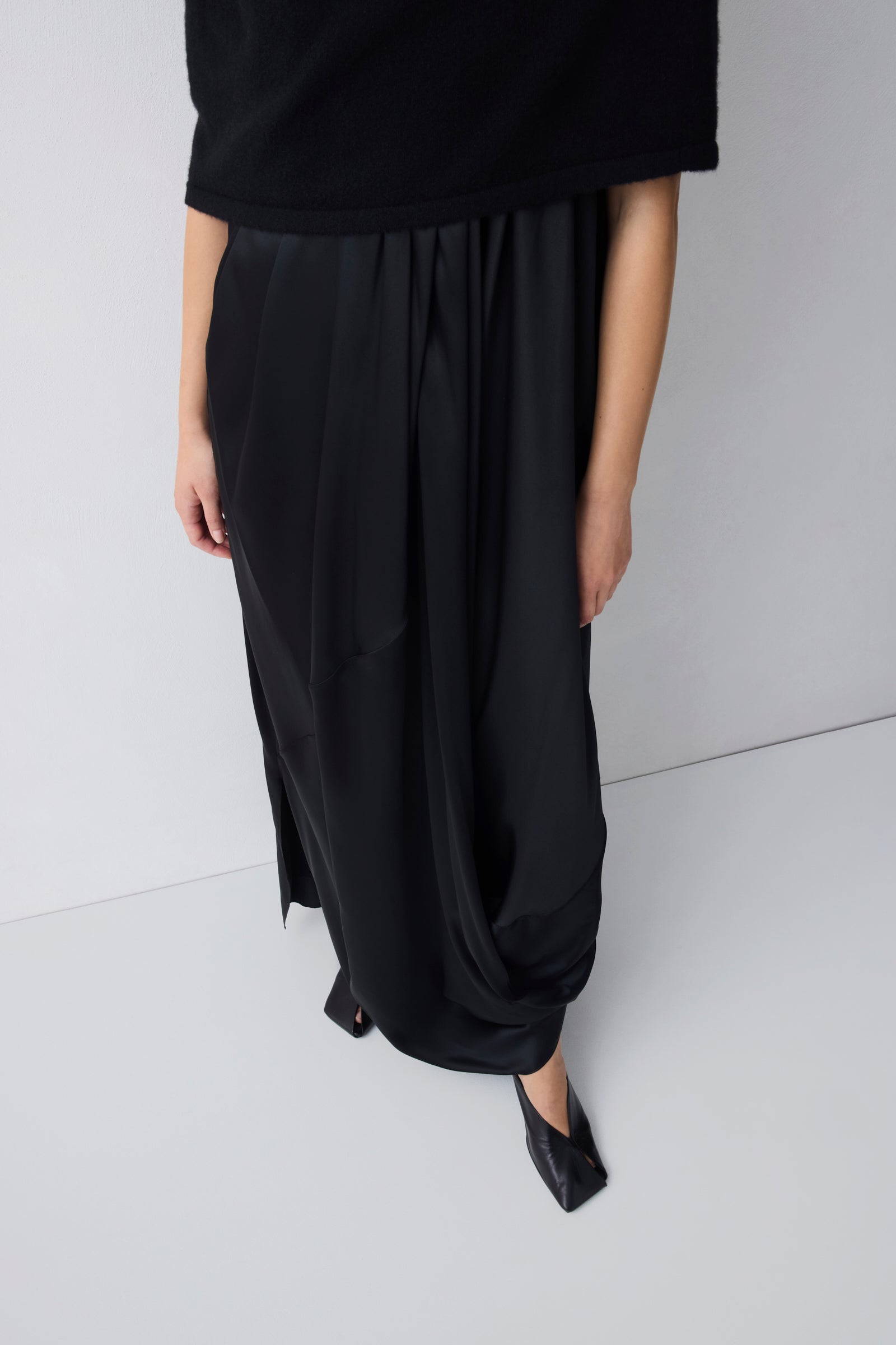Person wearing black wide-leg pants and a black top on a white background