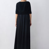 Person wearing a black dress standing against a white background