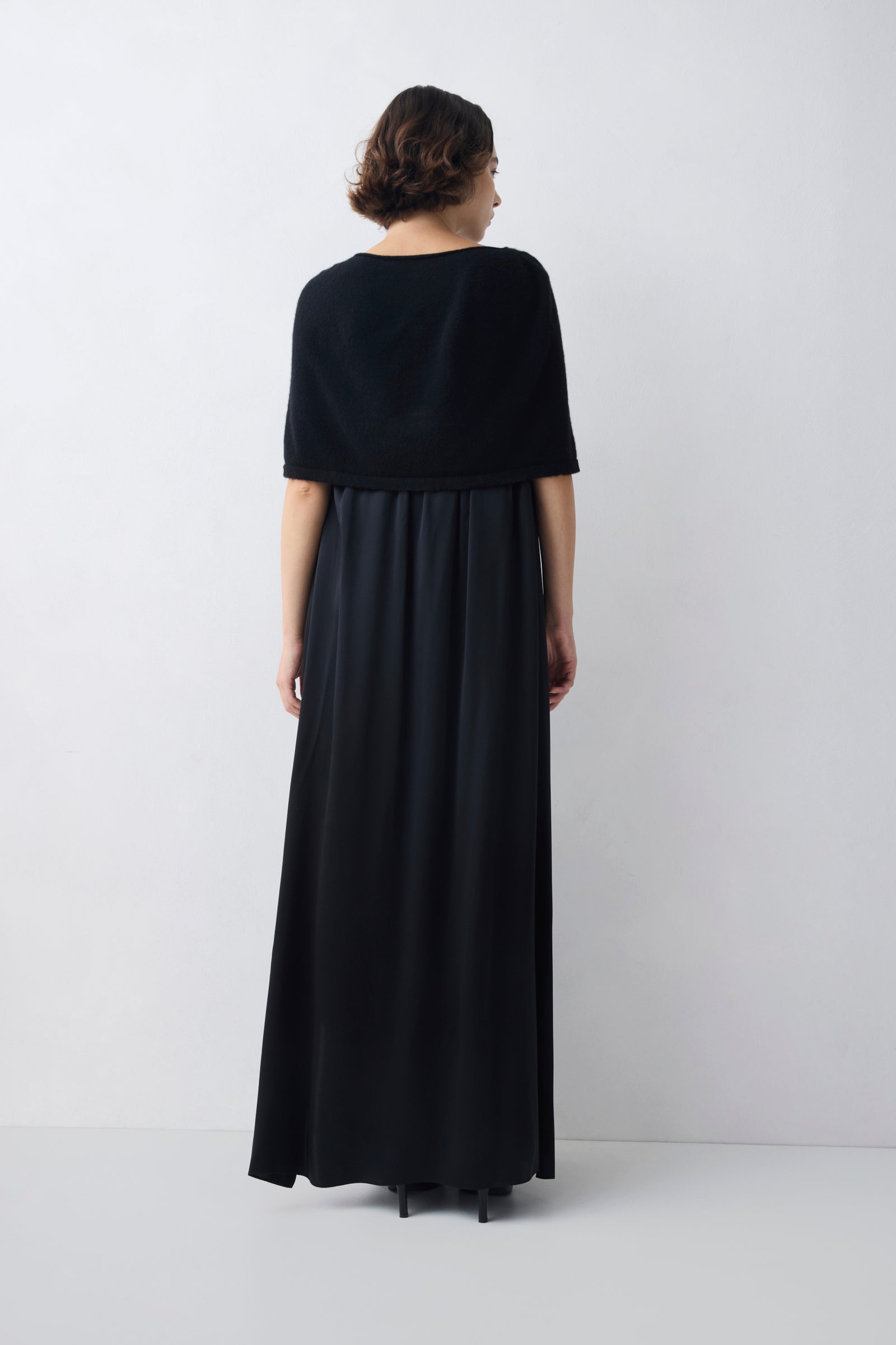 Person wearing a black dress standing against a white background