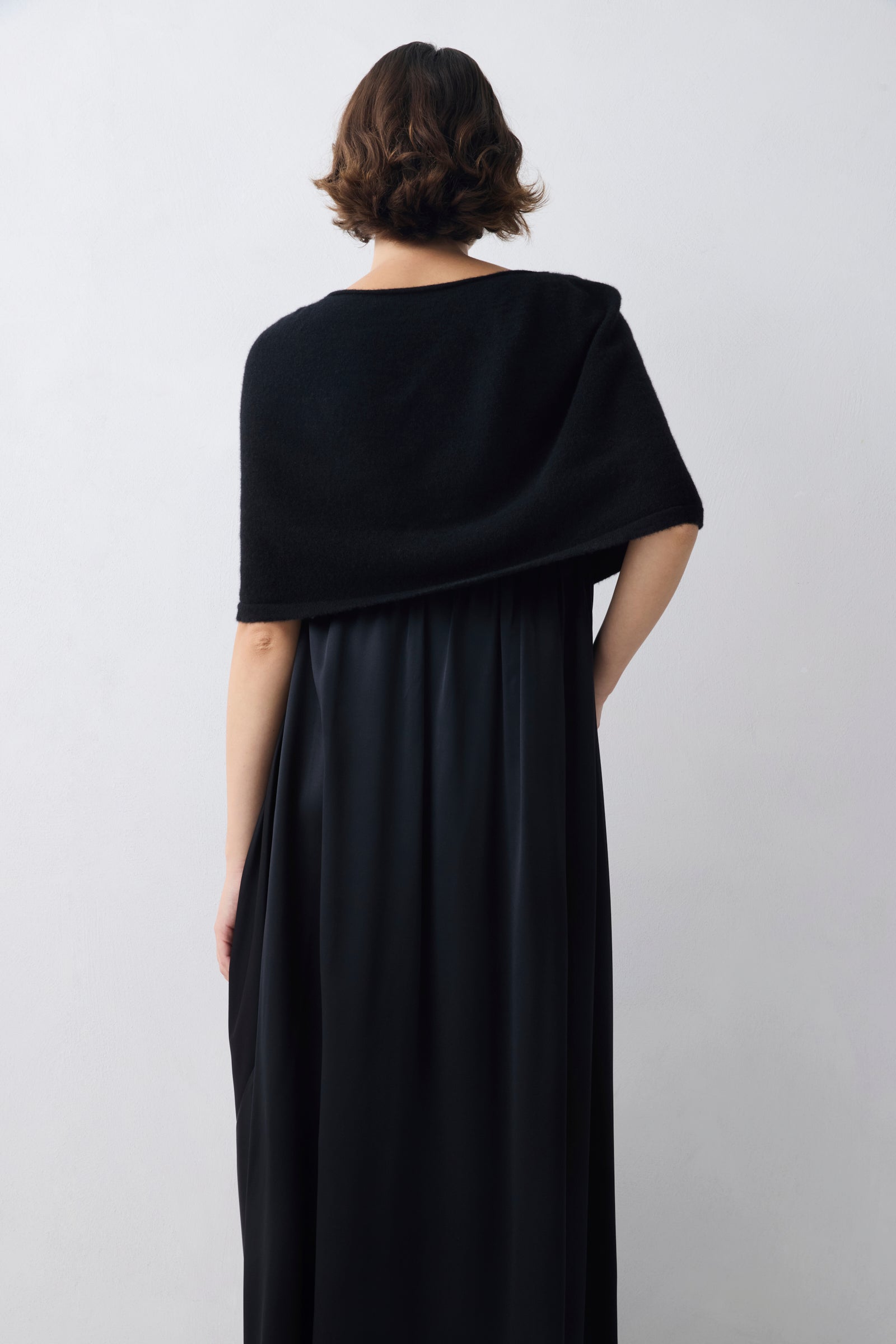 Person wearing a black dress against a white background