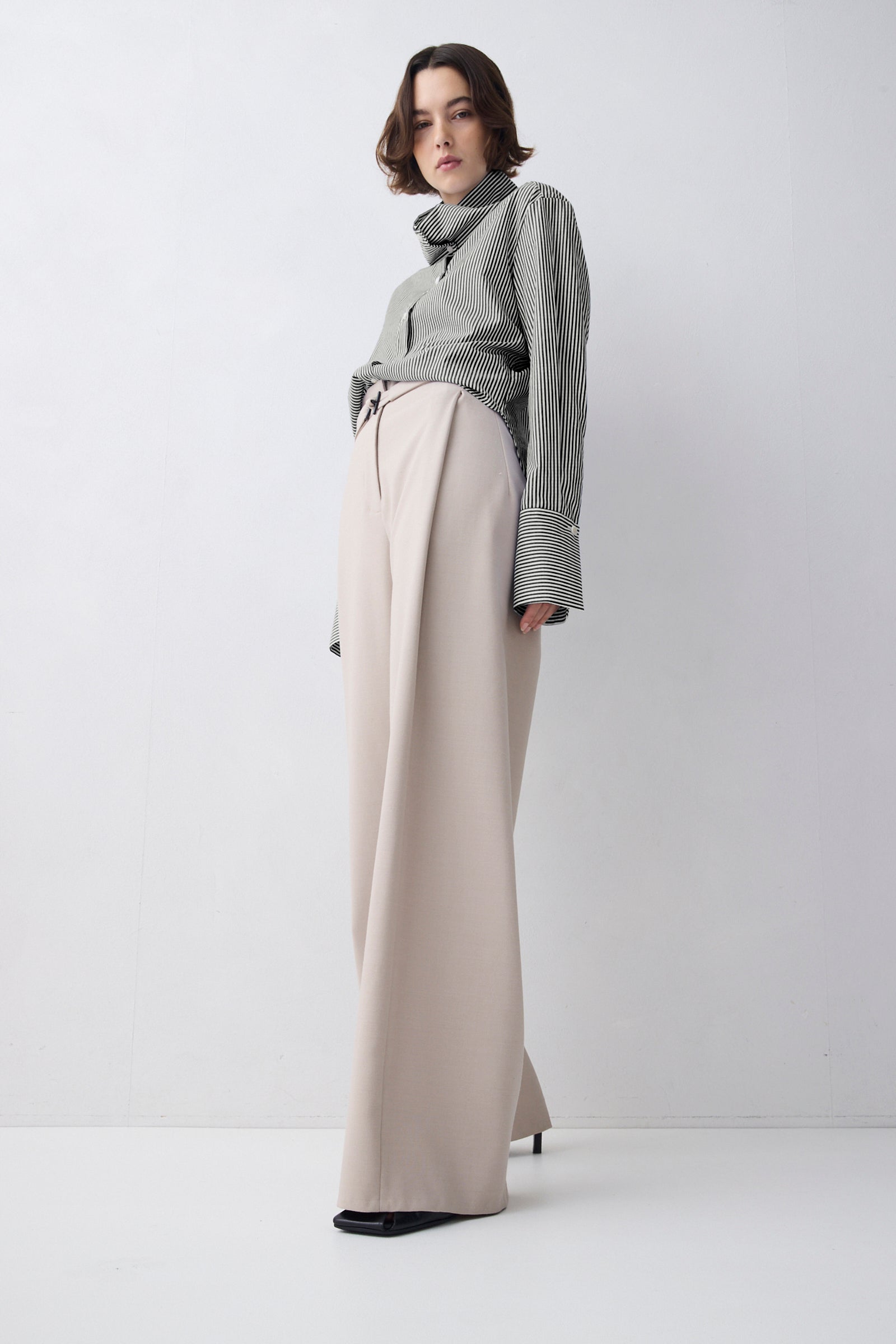 Person wearing a gray sweater and beige pants on a white background