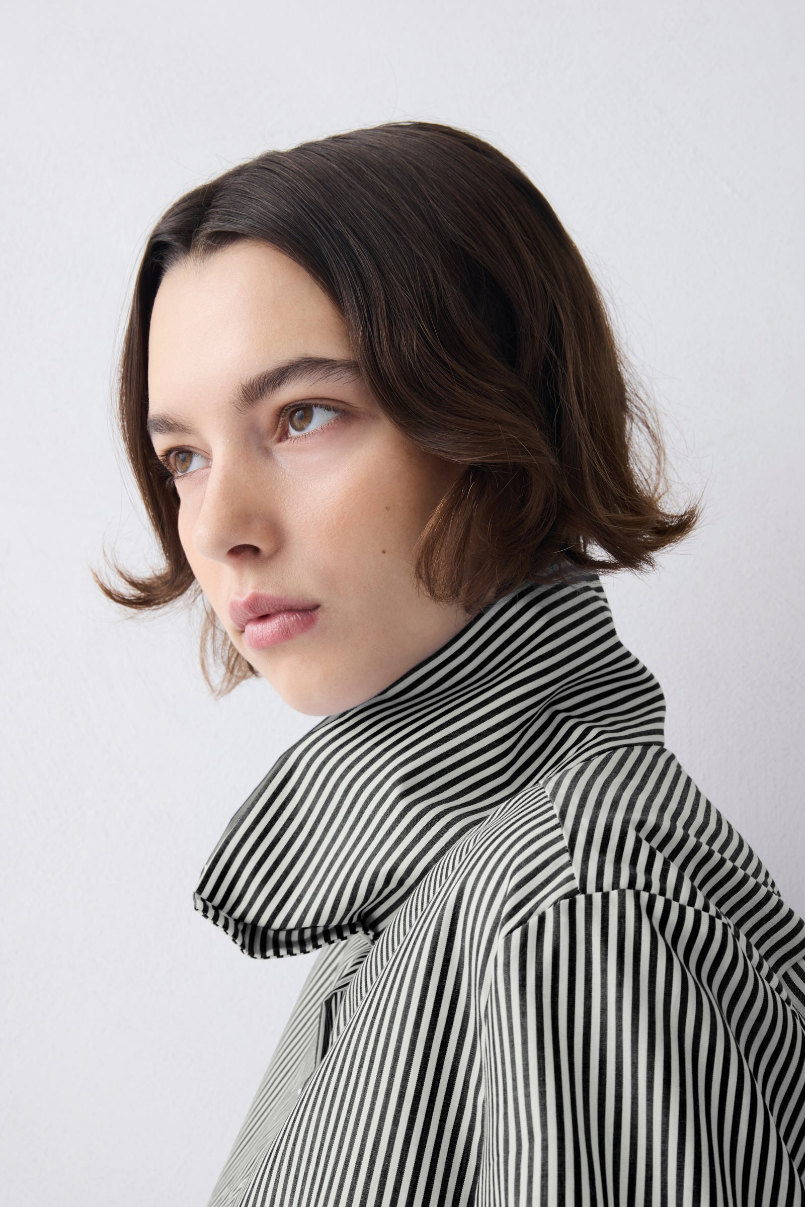 Woman wearing a black and white striped coat against a plain background