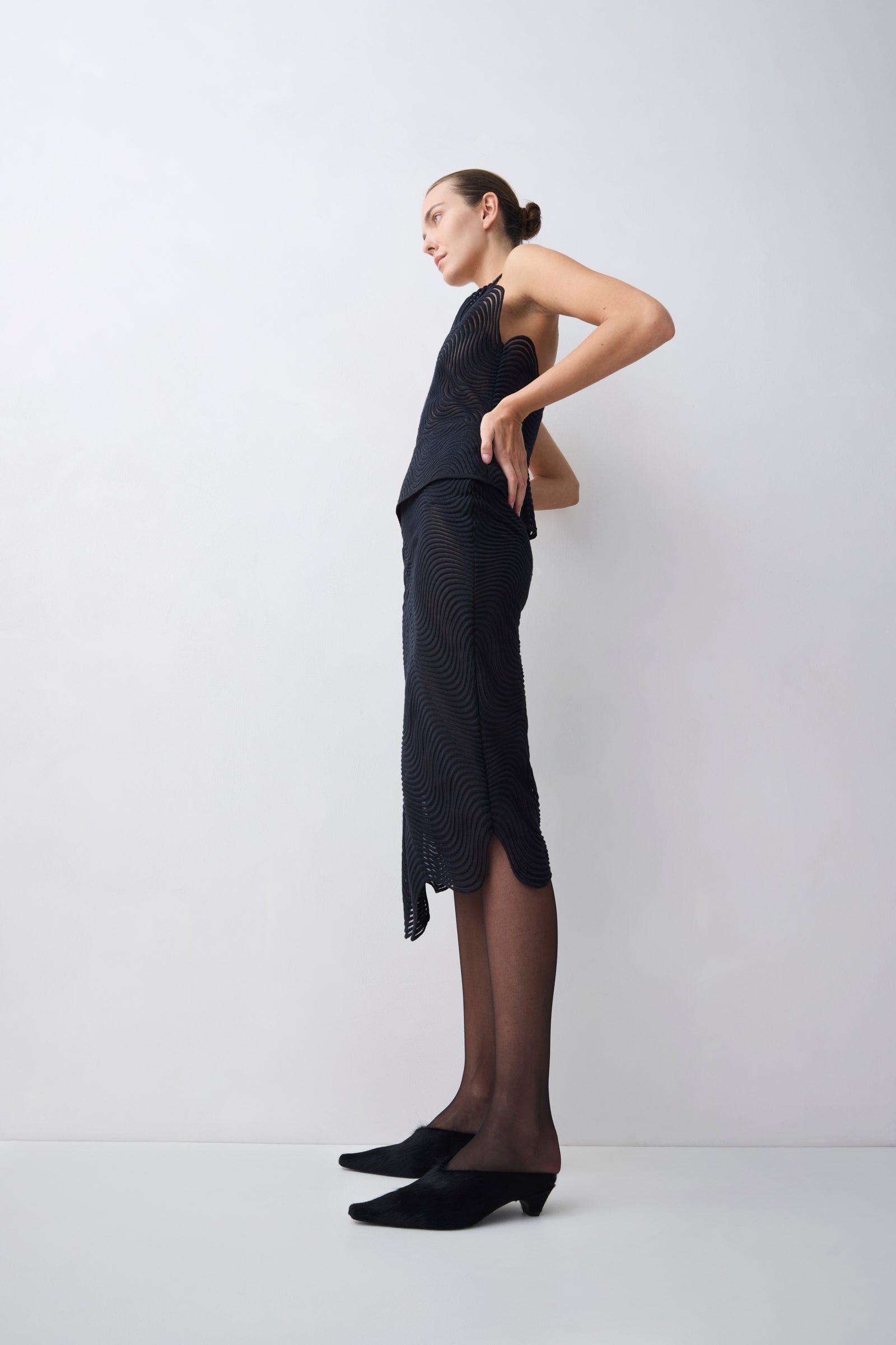 Woman wearing a black dress with sheer panels on a white background