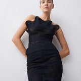 Woman wearing a black dress with a textured pattern against a white background