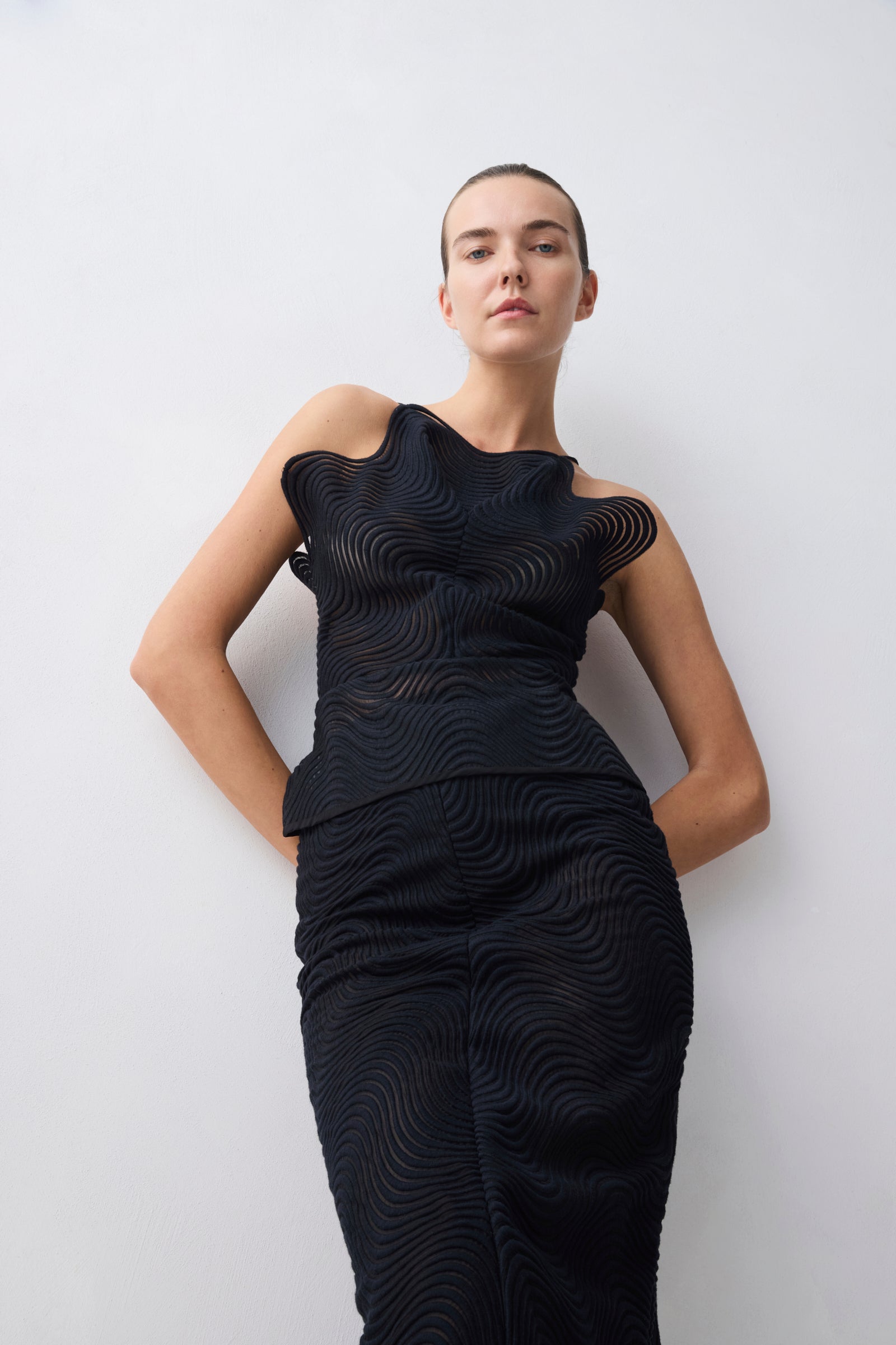 Woman wearing a black dress with a textured pattern against a white background