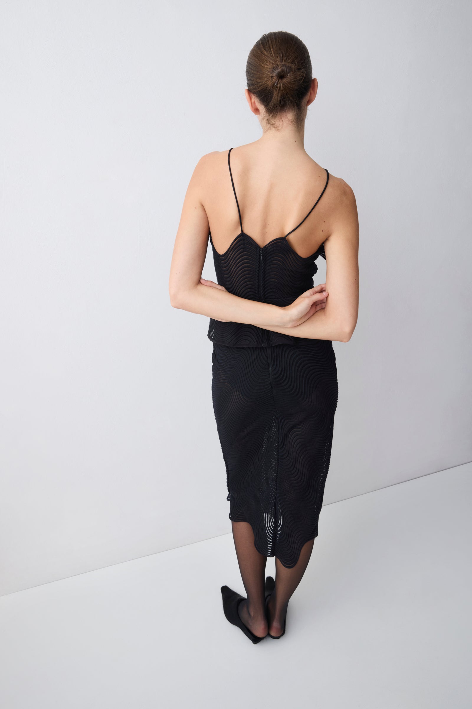 Woman wearing a black dress with thin straps on a white background