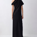 A model viewed from the back wearing a black one-shoulder maxi dress with short sleeves and a draped neckline, set against a plain light gray studio background.