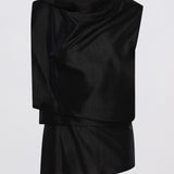 A black draped asymmetrical top with a high mock neck and layered ruffle details, shown against a plain light gray background.