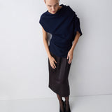 Person wearing a dark blue top and black skirt on a white background