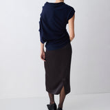Person wearing a navy top and black skirt on a white background