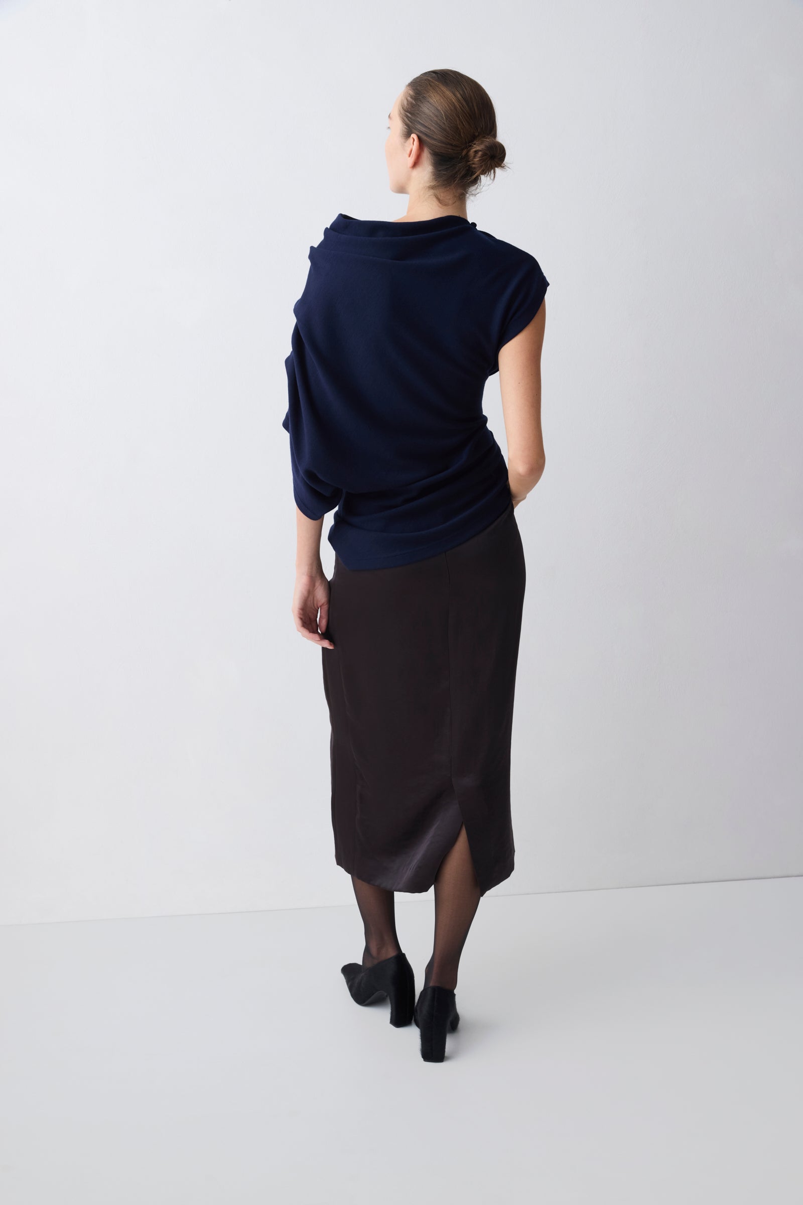 Person wearing a navy top and black skirt on a white background