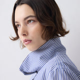 Woman wearing a blue and white striped shirt against a plain background