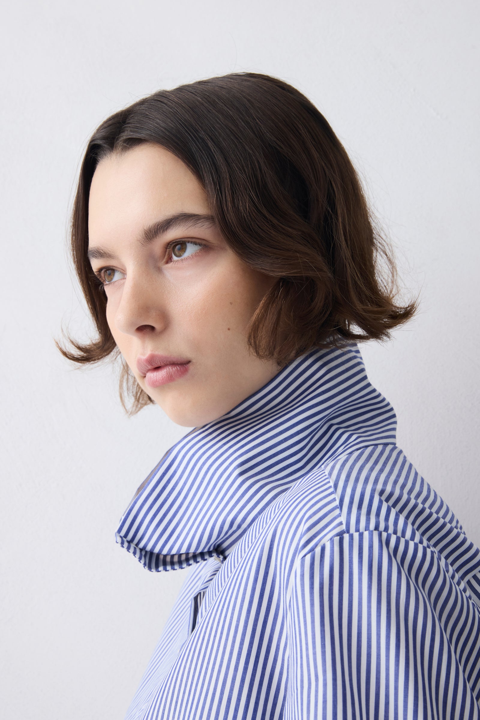 Woman wearing a blue and white striped shirt against a plain background