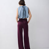 Person wearing a light blue sleeveless top and dark purple wide-leg pants on a white background