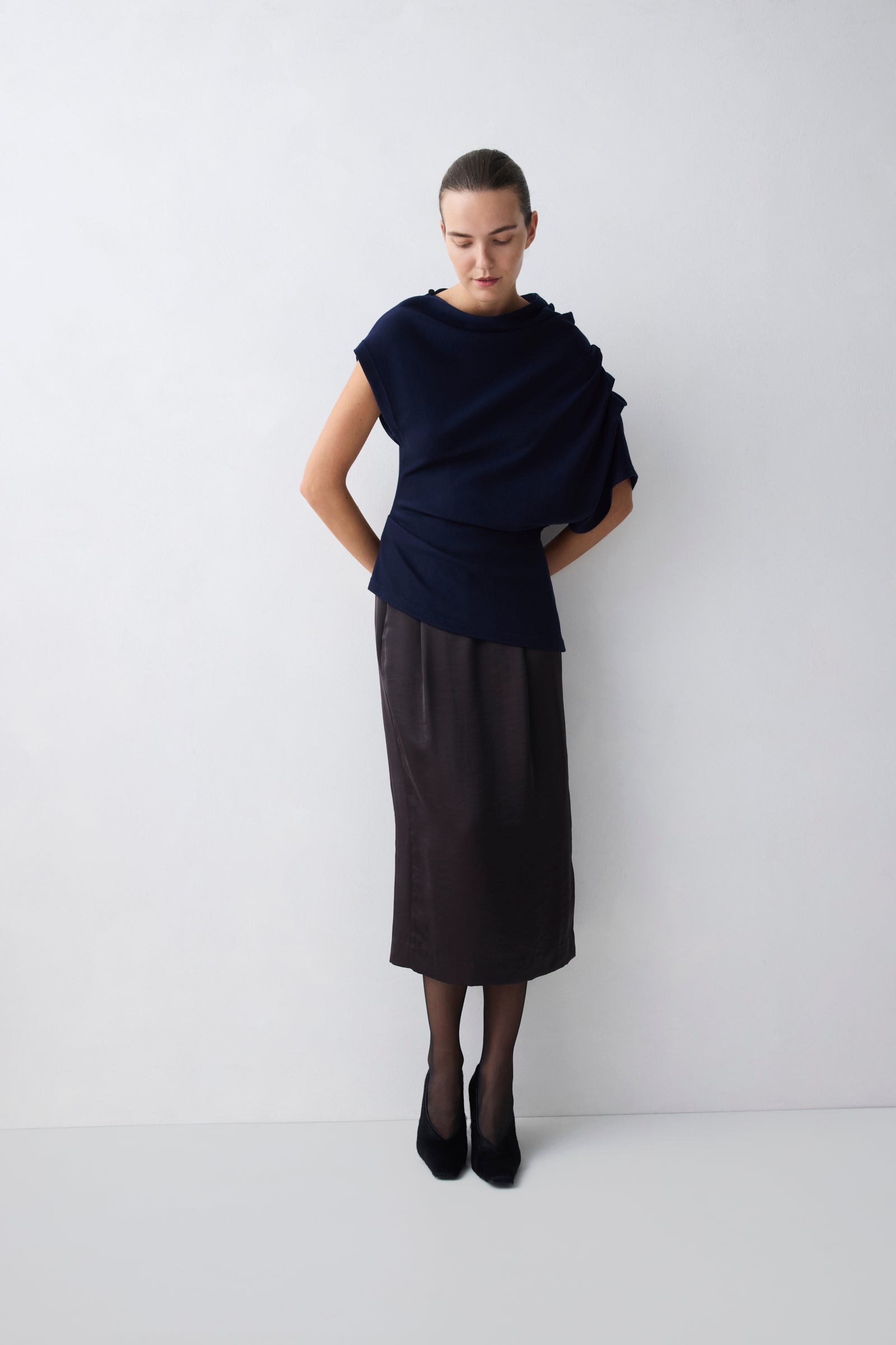 Person wearing a dark blue top and black skirt on a white background