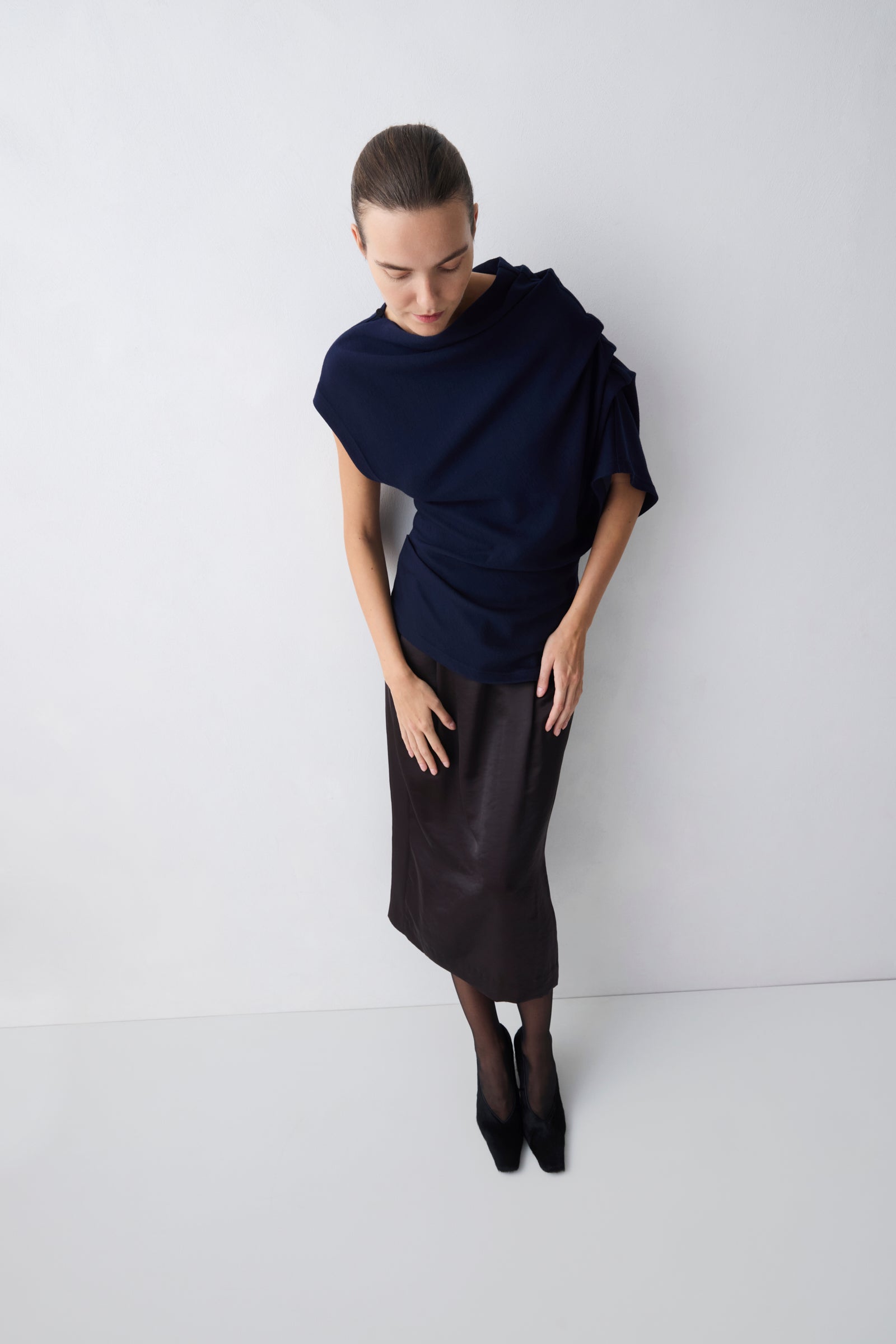 Person wearing a dark blue top and black skirt on a white background