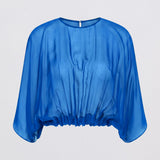 A bright blue sheer chiffon top with a round neckline and draped, elbow-length sleeves, shown against a light gray background.