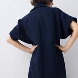 Person wearing a dark blue dress against a plain background