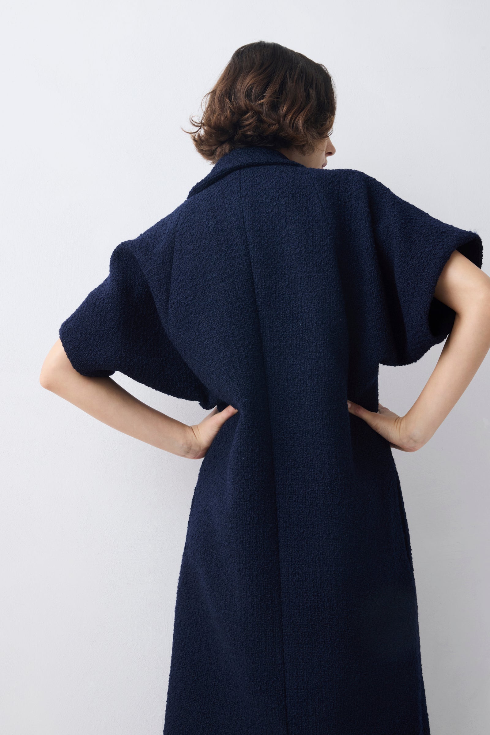 Person wearing a dark blue dress against a plain background